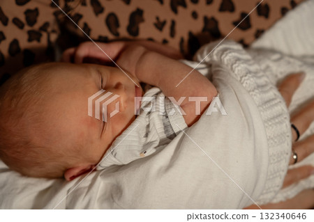 Mom gently cradles her sleeping baby in a cozy setting, showcasing a tender moment of bonding and warmth during an evening at home Mom gently cradles her sleeping baby in a cozy setting, showcasing a tender moment of bonding and warmth during an evening at home 132340646
