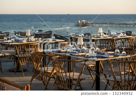 Stunning oceanfront dining scene with elegantly set tables and glassware Stunning oceanfront dining scene with elegantly set tables and glassware 132340932