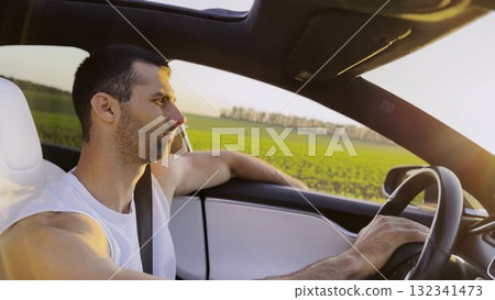 Profile of young handsome man driving a modern electric car with sunlight at background. Young male driver riding on electrical vehicle at countryside. Concept of journey and trip. Close up 132341473