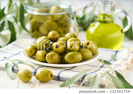 marinated pitted green olives and olive oil on a white kitchen table, selective focus. 132341734