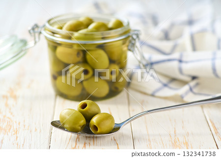 pitted olives in a jar on a white kitchen table, selective focus. pitted olives in a jar on a white kitchen table, selective focus. 132341738