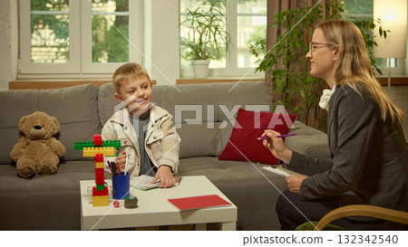 Smiling boy talking to psychologist during session with colorful creative materials Smiling boy talking to psychologist during session with colorful creative materials 132342540
