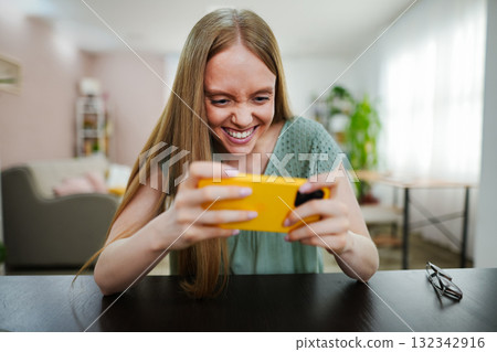 Young woman enjoying a game on her smartphone at home Young woman enjoying a game on her smartphone at home 132342916