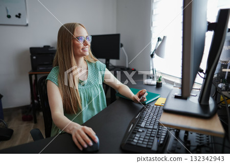 Focused woman working at her desk during bright daylight hours 132342943