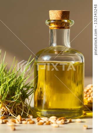 Glass bottle of golden oil surrounded by wheat grass and grains, symbolizing isolation and exclusion Glass bottle of golden oil surrounded by wheat grass and grains, symbolizing isolation and exclusion 132343248