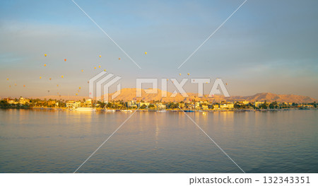 Hot Air Balloons Float Over West Bank of Luxor Egypt at Dawn from Nile Cruise. 132343351