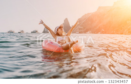Woman, swim ring, ocean. Happy young woman enjoys freedom floating on a donut swim ring in the ocean at sunset, copy space. Woman, swim ring, ocean. Happy young woman enjoys freedom floating on a donut swim ring in the ocean at sunset, copy space. 132343457