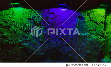 Rough plaster wall with heavy texture lit by green and blue neon, vivid moody glow creating dramatic abstract backdrop Rough plaster wall with heavy texture lit by green and blue neon, vivid moody glow creating dramatic abstract backdrop 132343578