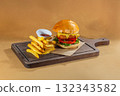 A fast food meal featuring a crispy fish fillet burger with mustard sauce, fresh tomato, and fried lettuce, served with a side of French fries 132343582