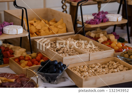 Gourmet Charcuterie Display with Pistachios, Cheeses, Olives, and Nuts Rustic White Wood Table Setting, Food Photography Gourmet Charcuterie Display with Pistachios, Cheeses, Olives, and Nuts Rustic White Wood Table Setting, Food Photography 132343952