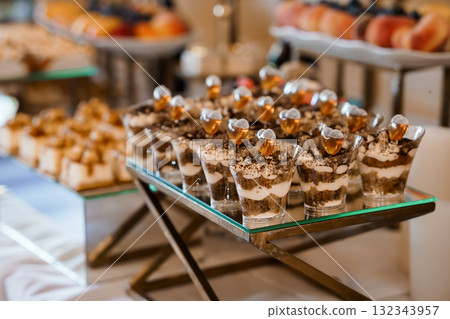 Elegant Chocolate Dessert Parfaits Display at Buffet. Rich Brown Tiramisu Cups, Glassware, Luxury Catering, Appetizers, Festive Celebration. Elegant Chocolate Dessert Parfaits Display at Buffet. Rich Brown Tiramisu Cups, Glassware, Luxury Catering, Appetizers, Festive Celebration. 132343957