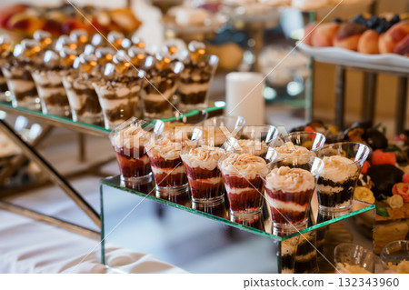 Elegant Dessert Display at Wedding Reception: Chocolate Mousse Parfaits, Glassware, Fruit Platter, Gold Accents, Luxurious Event Catering Style Elegant Dessert Display at Wedding Reception: Chocolate Mousse Parfaits, Glassware, Fruit Platter, Gold Accents, Luxurious Event Catering Style 132343960