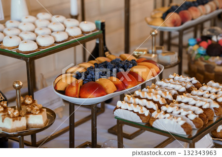 Elegant Dessert Table Spread with Pastries, Fruit, and Gold Accents Wedding Reception Food Display, White and Peach Tones 132343963