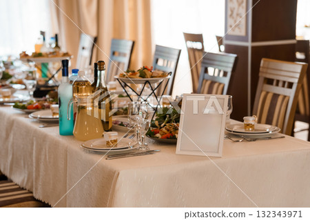 Elegant Wedding Reception Table Setting with White Linen, Salad Bowls, Place Cards, and Water Bottles Neutral Tone Celebration. Elegant Wedding Reception Table Setting with White Linen, Salad Bowls, Place Cards, and Water Bottles Neutral Tone Celebration. 132343971