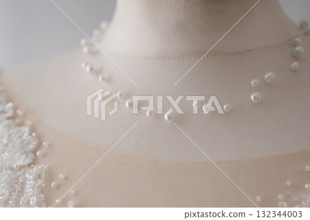 Delicate Pearl Necklace on Mannequin. Bridal Jewelry Close-up. Ivory Lace Gown Detail. Soft Focus Wedding Accessories. Elegant White Beads. Delicate Pearl Necklace on Mannequin. Bridal Jewelry Close-up. Ivory Lace Gown Detail. Soft Focus Wedding Accessories. Elegant White Beads. 132344003