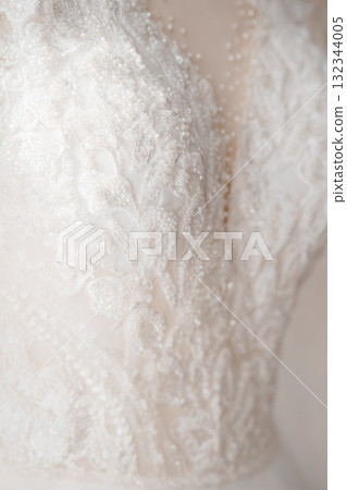 Intricate Ivory Lace Wedding Dress Bodice Detail, Close-Up View, Pearl Accents, Delicate Floral Pattern, Romantic Bridal Gown Texture. Intricate Ivory Lace Wedding Dress Bodice Detail, Close-Up View, Pearl Accents, Delicate Floral Pattern, Romantic Bridal Gown Texture. 132344005