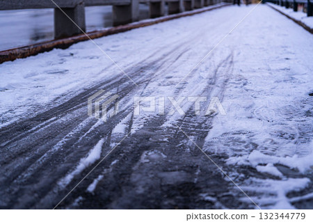 雪天早晨，冰凍瀝青上的自行車輪胎痕跡 132344779
