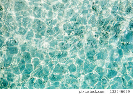 Clear turquoise water reflecting sunlight along a serene beach in the afternoon, inviting relaxation and enjoyment of nature's beauty 132346659