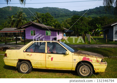 An old yellow car stands near a colorful house in the background on a sunny day in the countryside. Redang Island An old yellow car stands near a colorful house in the background on a sunny day in the countryside. Redang Island 132346794