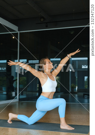 Woman practicing yoga in a modern studio during a calm morning session focusing on flexibility and strength through various poses 132347120