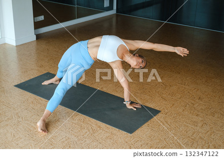 Woman practicing yoga in a modern studio, showcasing strength and flexibility during an evening yoga session 132347122
