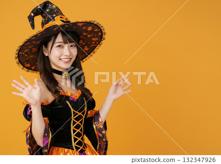 A woman dressed as a witch on an orange background A woman dressed as a witch on an orange background 132347926
