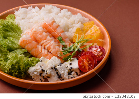 Bowl with shrimps, seafood, rice, oranges, tomatoes with sauce. Bowl with prawns 132348102