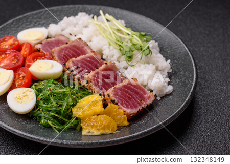 Seafood bowl, tuna tataki fillet slices with rice, oranges, tomatoes and sauce. Tuna bowl Seafood bowl, tuna tataki fillet slices with rice, oranges, tomatoes and sauce. Tuna bowl 132348149
