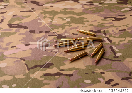 Machine gun cartridges on a camouflage background, military wallpaper. Camouflage background 132348262