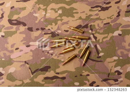 Machine gun cartridges on a camouflage background, military wallpaper. Camouflage background Machine gun cartridges on a camouflage background, military wallpaper. Camouflage background 132348263