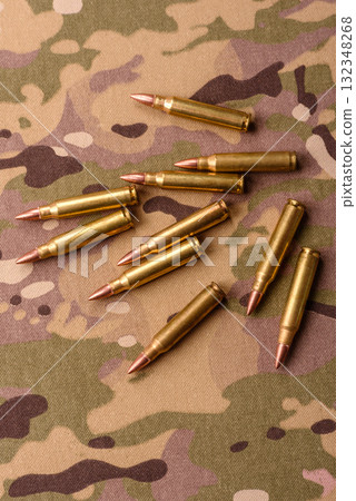 Machine gun cartridges on a camouflage background, military wallpaper. Camouflage background Machine gun cartridges on a camouflage background, military wallpaper. Camouflage background 132348268