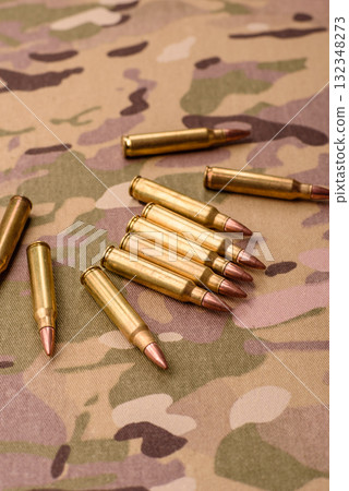 Machine gun cartridges on a camouflage background, military wallpaper. Camouflage background 132348273