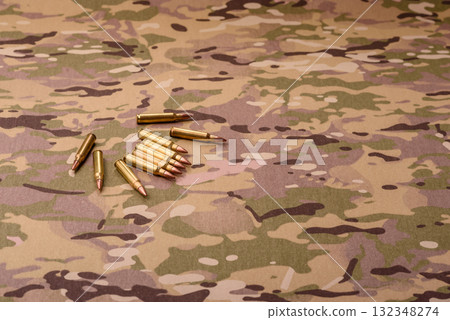 Machine gun cartridges on a camouflage background, military wallpaper. Camouflage background Machine gun cartridges on a camouflage background, military wallpaper. Camouflage background 132348274