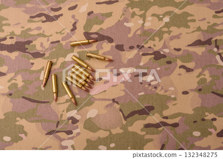Machine gun cartridges on a camouflage background, military wallpaper. Camouflage background Machine gun cartridges on a camouflage background, military wallpaper. Camouflage background 132348275