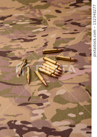 Machine gun cartridges on a camouflage background, military wallpaper. Camouflage background Machine gun cartridges on a camouflage background, military wallpaper. Camouflage background 132348277