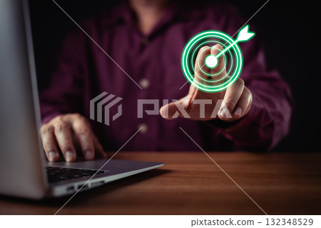 person in shirt uses a laptop while digitally pressing a glowing green target icon with an arrow, symbolizing precision, achievement, success, goal setting, and business focus in technology. person in shirt uses a laptop while digitally pressing a glowing green target icon with an arrow, symbolizing precision, achievement, success, goal setting, and business focus in technology. 132348529