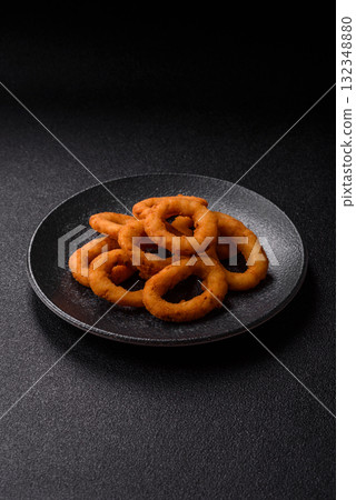 Onion rings or fried squid in breadcrumbs with sauce, takeaway food. Onion rings fried 132348880