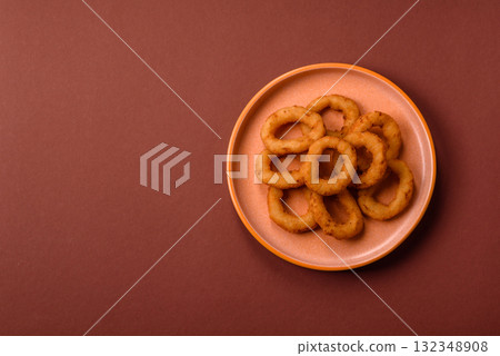 Onion rings or fried squid in breadcrumbs with sauce, takeaway food. Onion rings fried 132348908