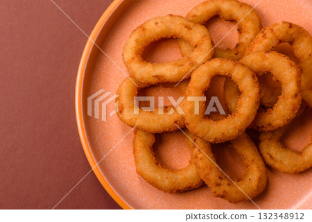 Onion rings or fried squid in breadcrumbs with sauce, takeaway food. Onion rings fried 132348912