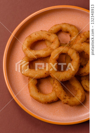 Onion rings or fried squid in breadcrumbs with sauce, takeaway food. Onion rings fried 132348913