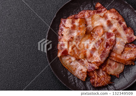 Cooked crispy fried pork bacon strips for a hearty breakfast. Fried bacon strips Cooked crispy fried pork bacon strips for a hearty breakfast. Fried bacon strips 132349509