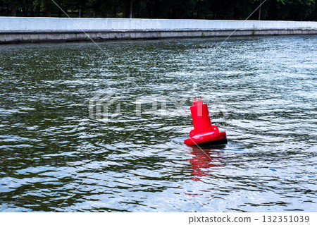 A Red Buoy Floating Gracefully on the Calm Waters Surface Beneath the Sky A Red Buoy Floating Gracefully on the Calm Waters Surface Beneath the Sky 132351039