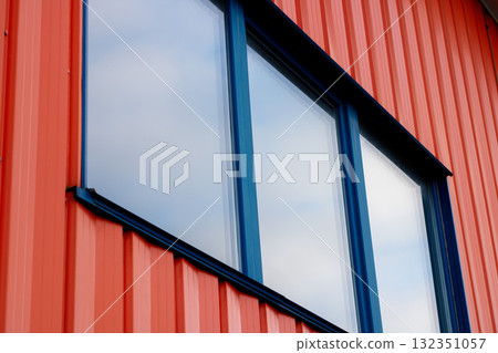 Modern building window with blue trim on a vibrant red wall 132351057
