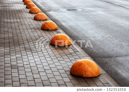 A Line of Orange Traffic Barriers Placed on a Paved Sidewalk Surface 132351058