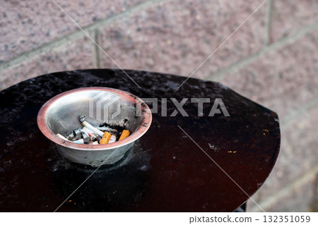 The Cigarette Ashtray holds Butts on the Outdoor Table surface 132351059