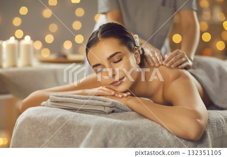 Beautiful young woman relaxing and enjoying professional back massage at a spa salon Beautiful young woman relaxing and enjoying professional back massage at a spa salon 132351105