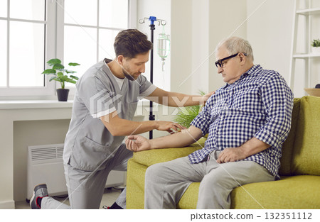 Nurse or doctor in uniform gives intravenous vitamin therapy infusion to senior patient Nurse or doctor in uniform gives intravenous vitamin therapy infusion to senior patient 132351112