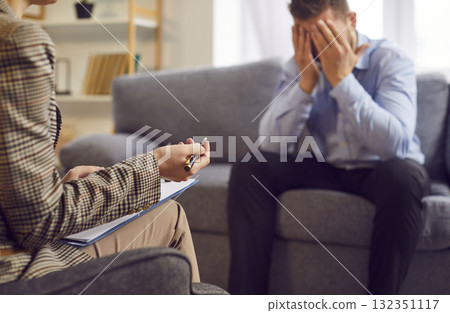 Stressed male patient with head in his hands on psychotherapy with his therapist. Stressed male patient with head in his hands on psychotherapy with his therapist. 132351117