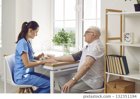 Doctor helping senior male patient and measuring his blood pressure with tonometer Doctor helping senior male patient and measuring his blood pressure with tonometer 132351194
