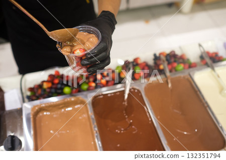Making chocolate treats with fresh fruits in a pastry shop during a busy day. Sweets Making chocolate treats with fresh fruits in a pastry shop during a busy day. Sweets 132351794